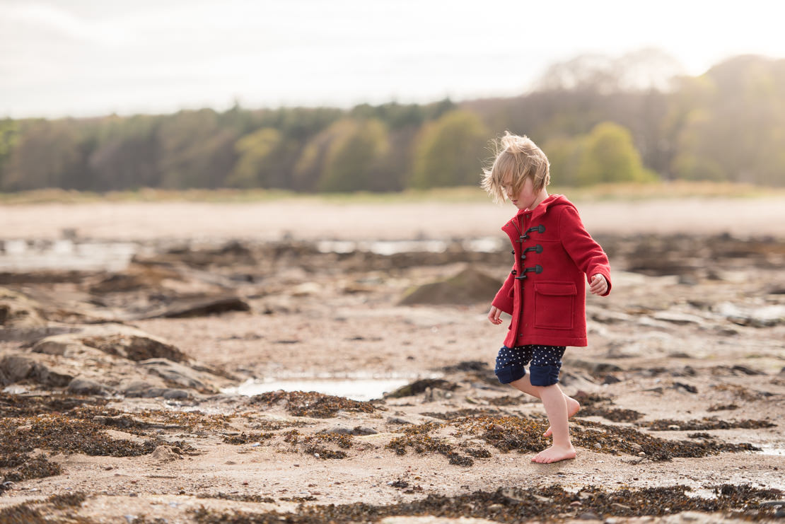 little girl in red coat and bare feet on Tyningham beach