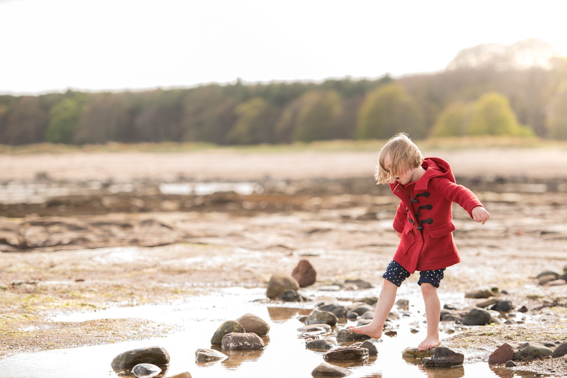 little girl walking barefoot through rock pools