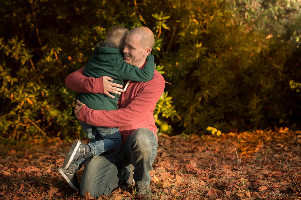 Family photographer Edinburgh - Dad giving 5 year old boy a big hug in autumn leaves