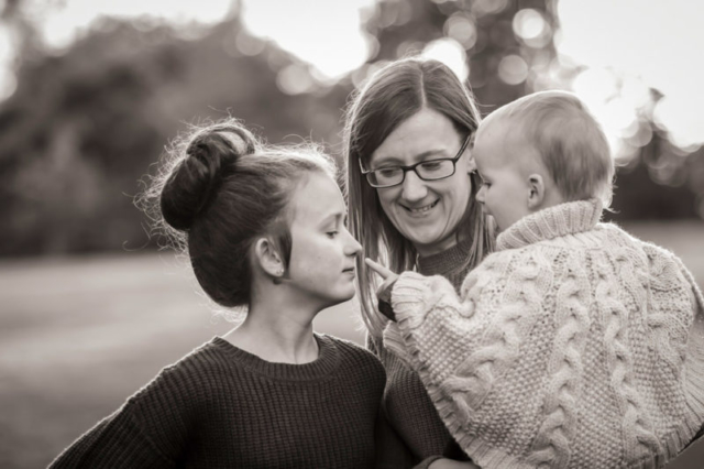 Family photographer Edinburgh - mother holding toddler who is pointing at her big sister