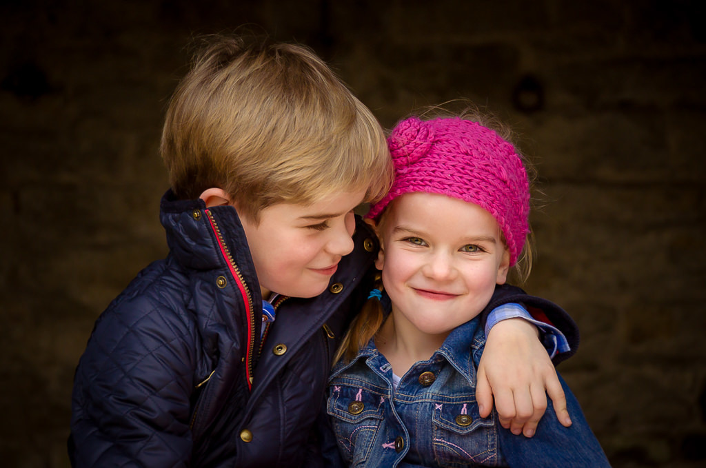 Family photographer Edinburgh - big brother hugging little sister who is wearing a pink headband