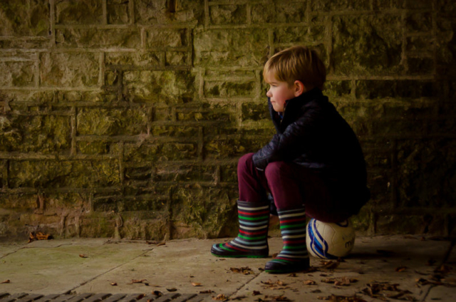 Family photographer Edinburgh - little boy in striped wellies sitting on a football