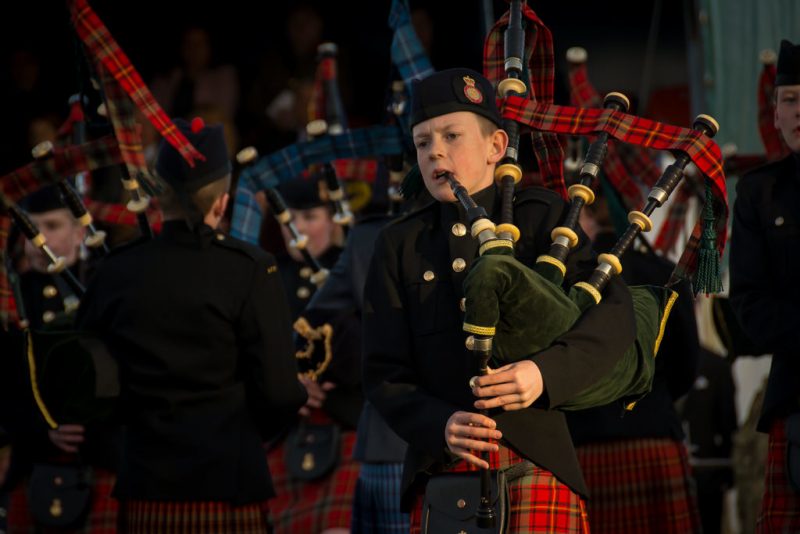 Family photographer Edinburgh - boy playing the bagpipes at Edinburgh Castle in red tartan Army Cadet kilt uniform