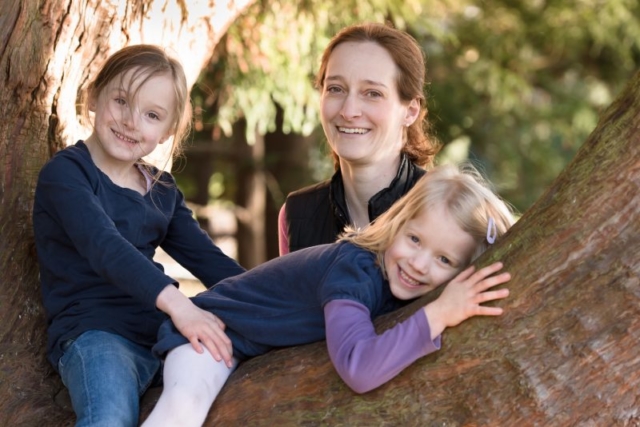 Family photographer Edinburgh - mother standing behind two little daughters in a tree