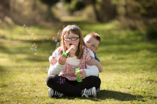Family photographer Edinburgh - 8 year old girl and 5 year old brother sitting blowing bubbles in the evening sunshine at Lauriston Castle, Edinburgh