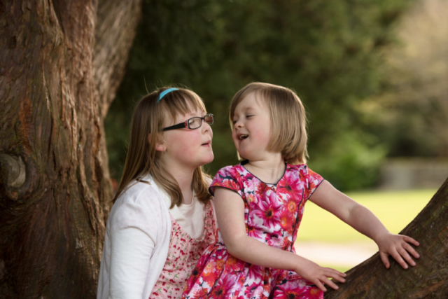 Family photographer Edinburgh - two little girls sitting in a tree laughing with each other