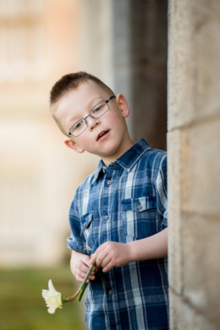 Family photographer Edinburgh - little boyin blue check shirt with glasses holding a daffodil