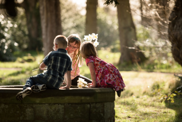 Family photographer Edinburgh - two little girls and little boy sitting on the well at Lauriston Castle in the evening sunshine
