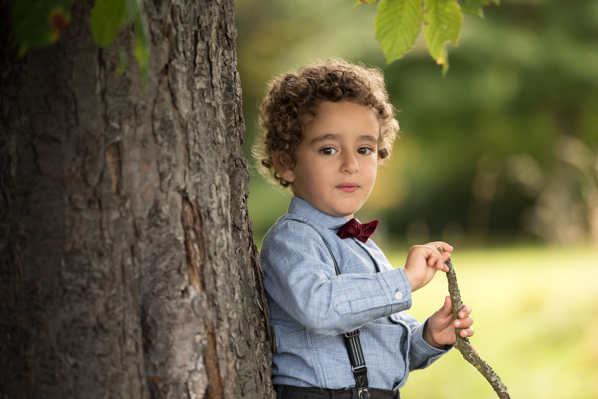 Family portraits Edinburgh - little boy with bow tie standing under tree