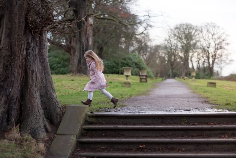 little girl in pink coat running playing hide and seek