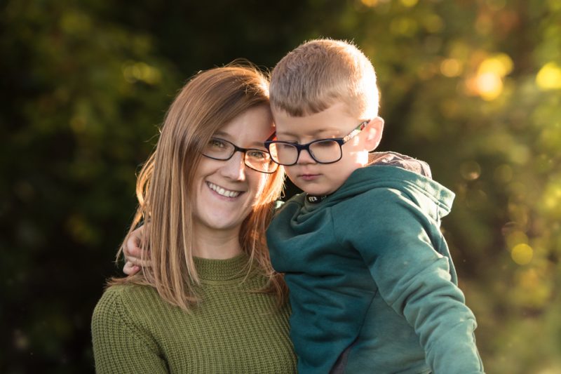 little boy with glasses being held by his mother