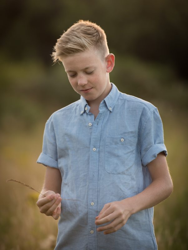 Family Photographer Edinburgh - Young boy in blue shirt looking down in grassy field