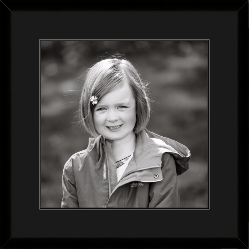 Family photographer Edinburgh - Donna Green - black and white portrait photograph of little girl with daisy in hair in black wooden frame