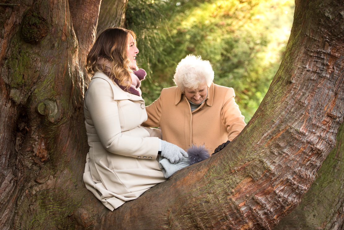 Edinburgh portrait photography - grownup daughter sitting in tree, laughing with her mother