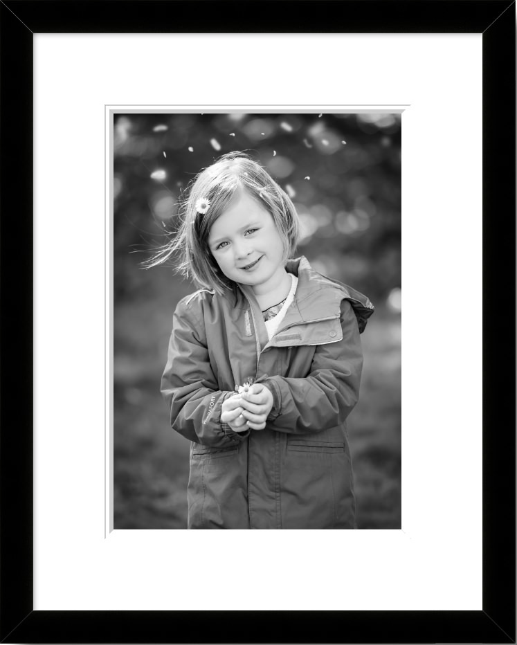 Black and white framed portrait of little girl holding daisy