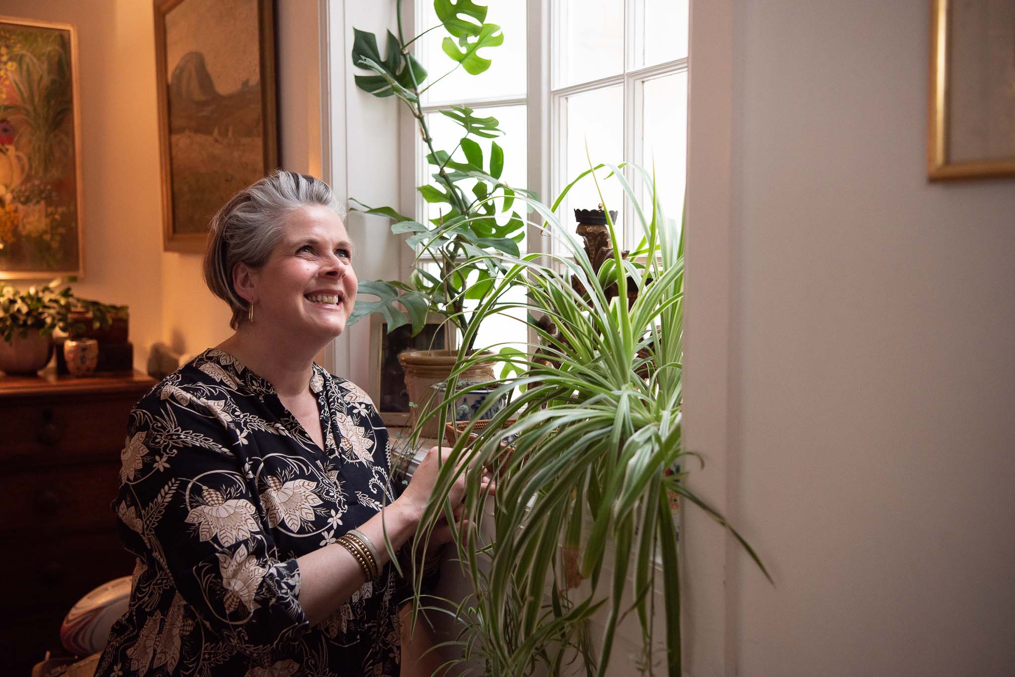 Brand photography in Scotland showing woman with spider plants in hall window
