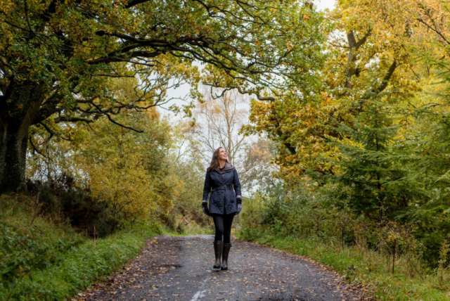 Natural brand photography photoshoot for business coach in Edinburgh, Scotland - woman walking down road under trees with autumn leaves
