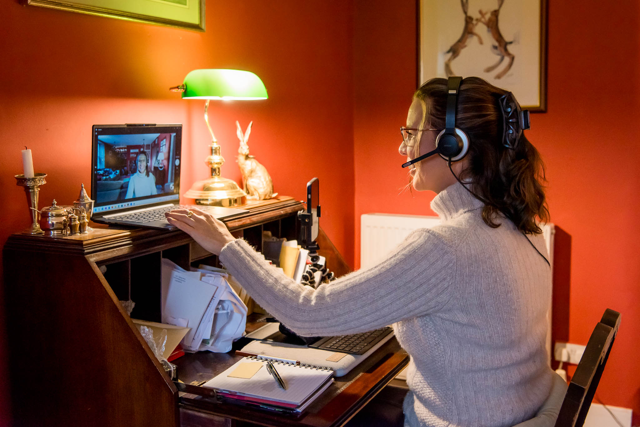 How to take business photos for a business coach, demonstrated by an image from a brand photography session of a woman sitting at an antique desk in Edinburgh, Scotland, on a zoom call with a client