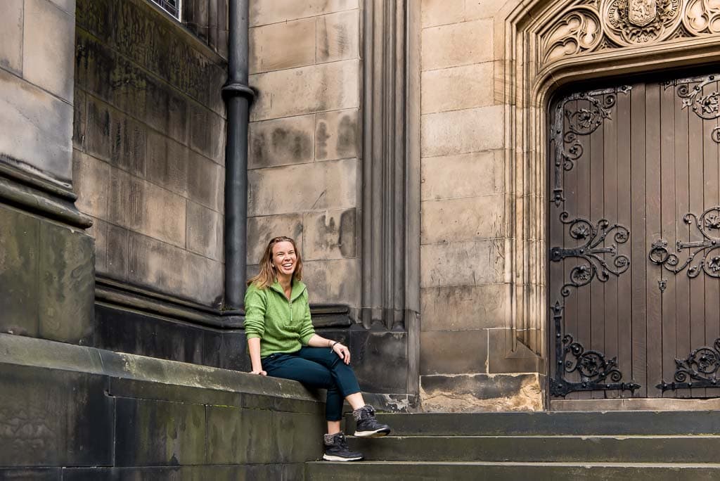 Brand photoshoot in Edinburgh, Scotland, with a small business owner seated on stone steps beside St Giles Catherdral on the Royal Mile, a historic building.