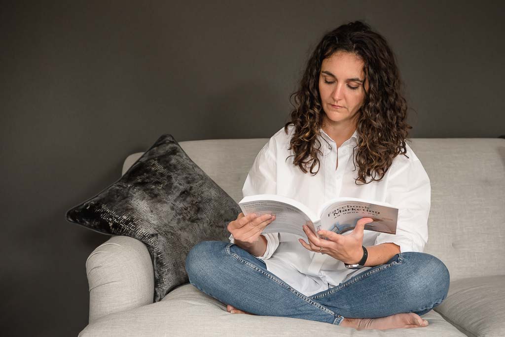 Brand photographer Aberdeen woman sitting on couch cross-legged reading book