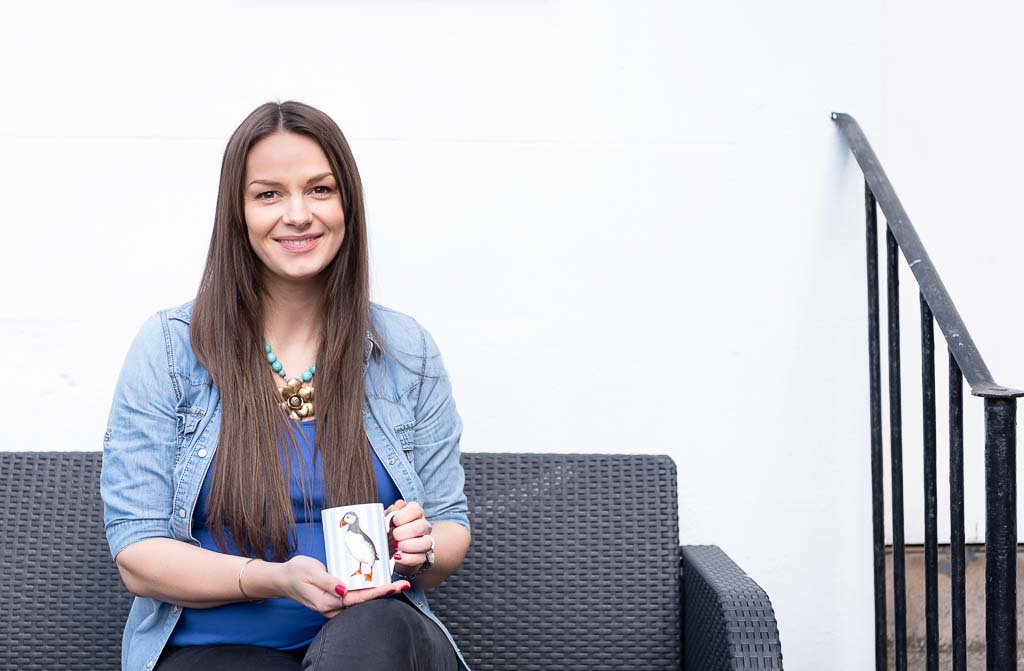 Brand photographer Edinburgh photo shoot with woman sitting down on couch outside holding mug of coffee