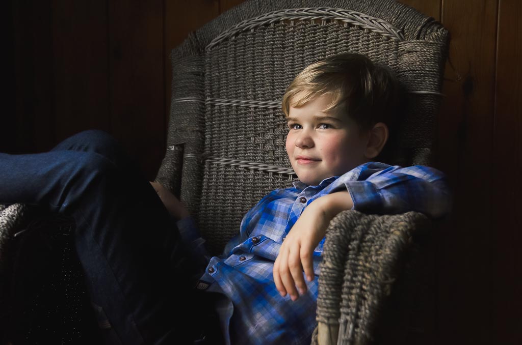 Family photographer Edinburgh shoot for young boy in blue checked shirt sitting on wicker chair