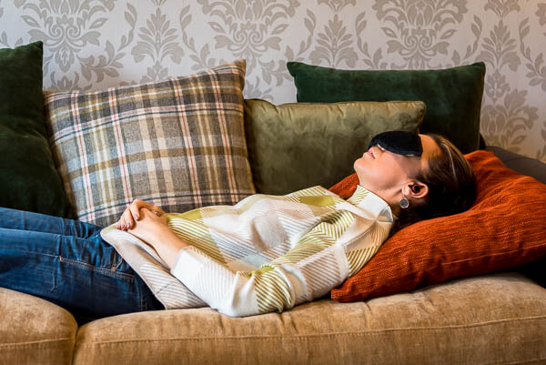 How to take business photos for a life coach, shown by life coach woman lying down on couch with eye mask on, meditating