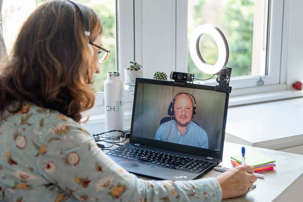 How to take business photos for virtual assistants showing woman with long brown hair sitting at her desk in Edinburgh, Scotland, with a laptop and ring light showing her on a zoom call with a client