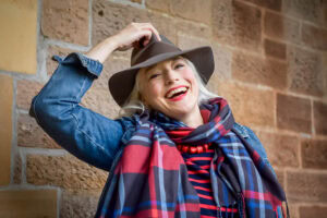 Headshot in Edinburgh, Scotland, of a creative writer woman with long white hair wearing a fedora hat