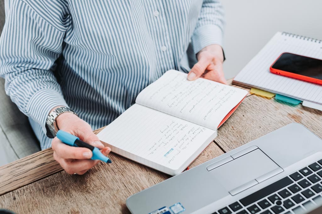 Executive assistant Sarah Whigham writing in her notebook during her Edinburgh brand photography session, Scotland