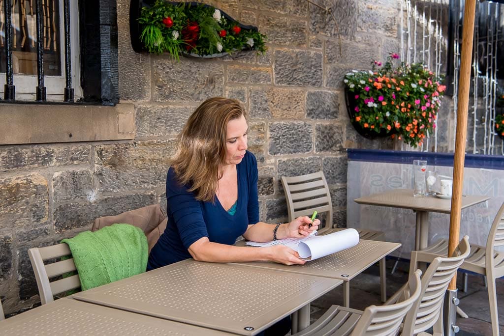 Brand photography client working at an outdoor café table in Edinburgh, Scotland, photographed in a quiet stone courtyard setting