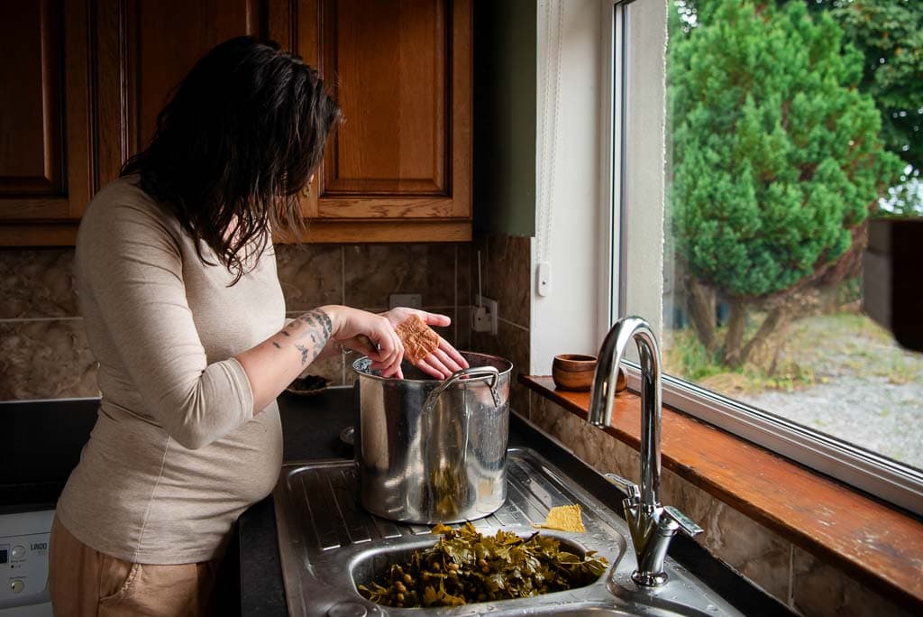 Heritage craftswoman examining material steeped in natural dye made in her kitchen on the Moray coast, an image designed to show the value of your work, photographed by a brand photographer in Scotland.