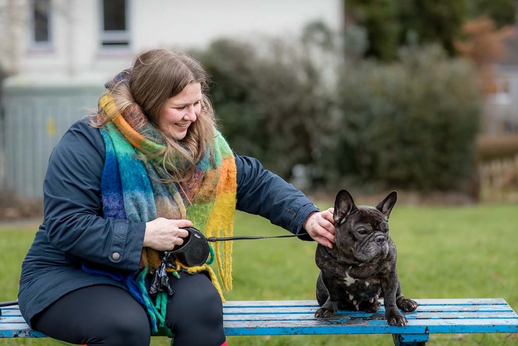 A female business owner smiling as she strokes her dog during a brand photography session with Edinburgh brand photographer Donna Green in Scotland