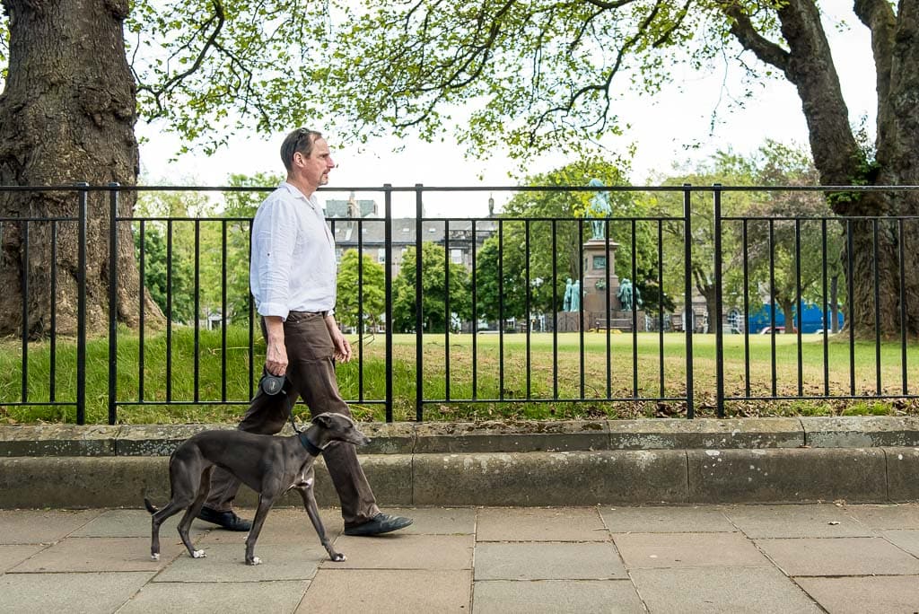 A male business owner walking his dog in the centre of Edinburgh, Scotland, during a session with brand photographer Donna Green